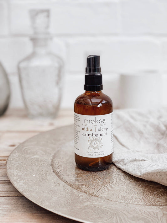 Bottle of moksa Nidra & Sleep Calming Mist on a wooden surface with a neutral background